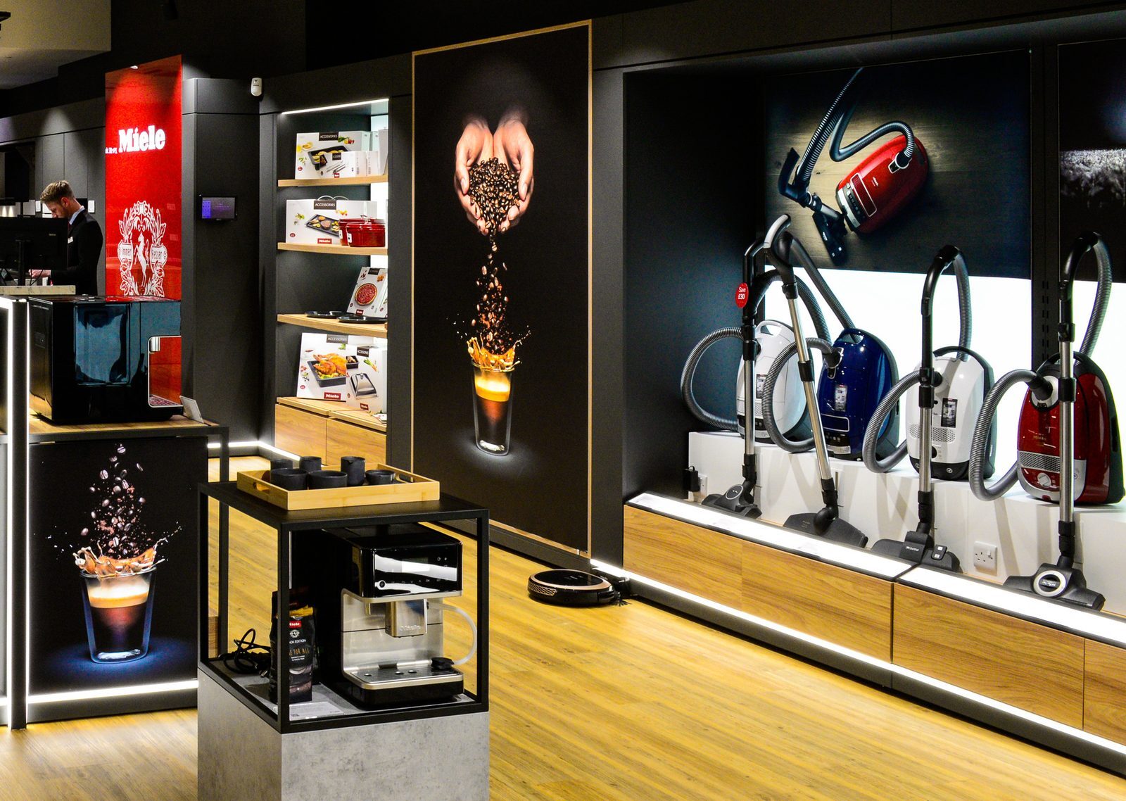 Miele in-store display of coffee machines and a row of canister vacuum cleaners